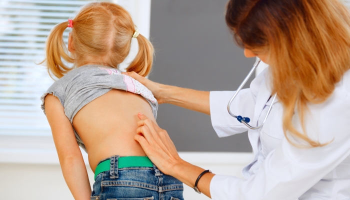 Pediatrician examining little girl with back problems