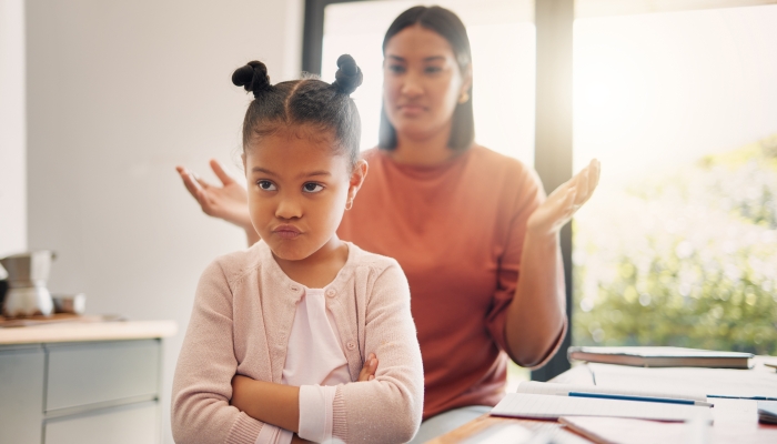 Stubborn little girl looking unhappy with her scolding mother.