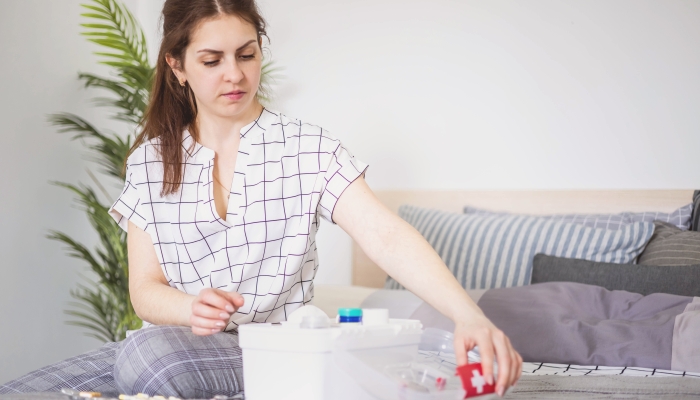 Female housewife checking medicines at domestic first aid kit.