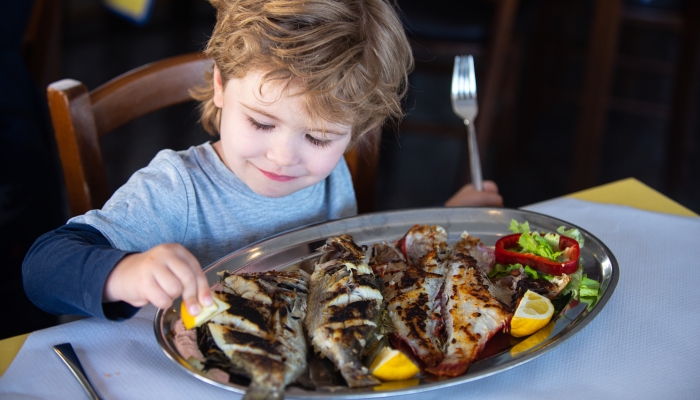 Child wuth lemon and fish plate meal.