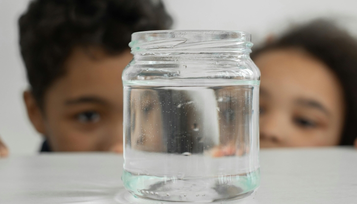 Children looking at glass jar with water