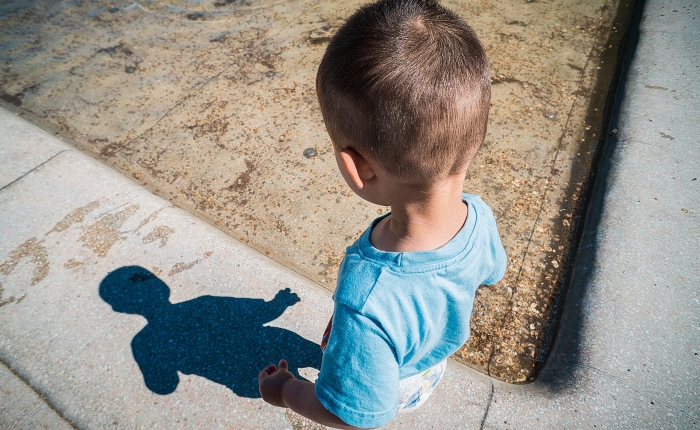 Boy looking at shadow on sidewalk