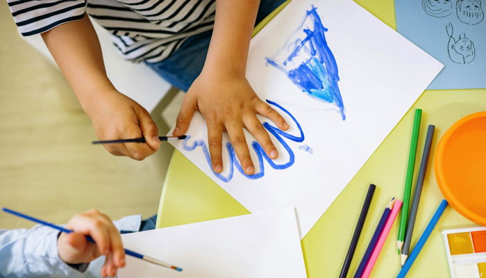 A child tracing their hand with blue paint.