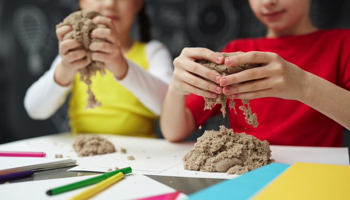 Two kids playing with kinetic sand.