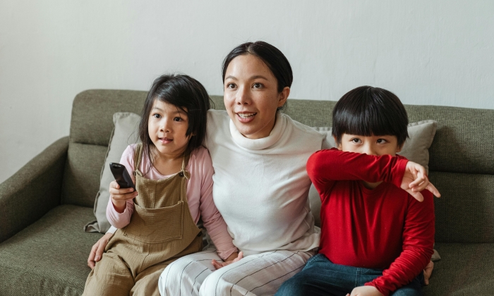 Happy Asian mother and kids spending time together on sofa