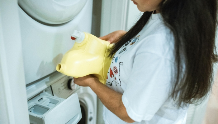A-Woman-in-White-T-shirt-Holding-Yellow-Plastic-Bottle-Near-a-Washing-Machine-2