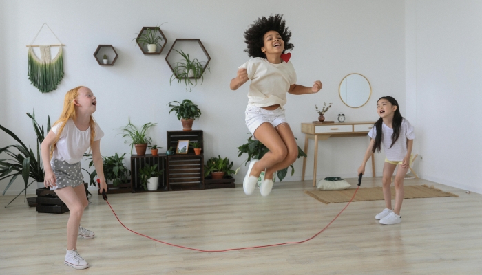 Black girl jumping over rope while playing with friends
