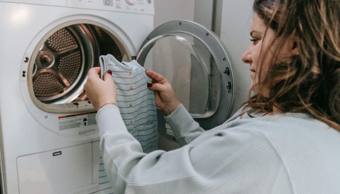 Happy mother washing baby clothes in machine