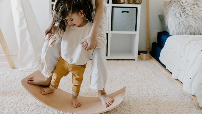 Mother helping child with balance training exercises on a balance board