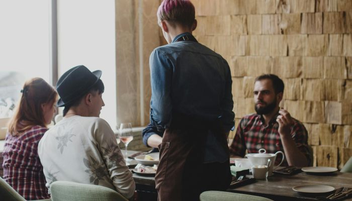 Focused waiter talking with clients in restaurant