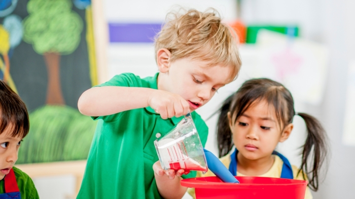 Boy learning how to pour and measure through sand play