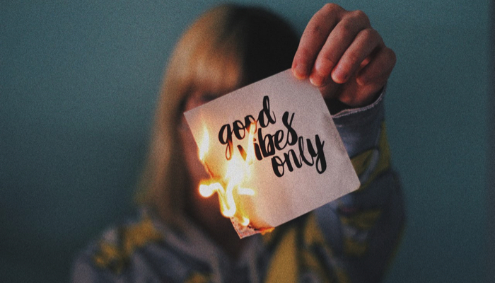 Woman burning a piece of paper with the words  "good vibes only"