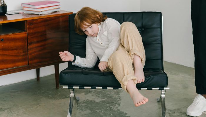 A Boy in White Long Sleeves Sitting on a Chair