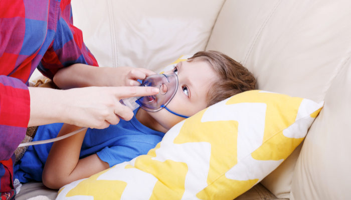 A mother holding a nebulizer mask for her son.