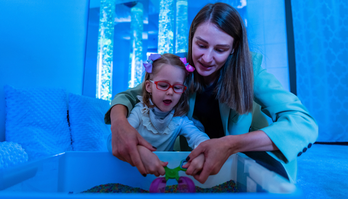 A little girl in a sensory room with a therapist.